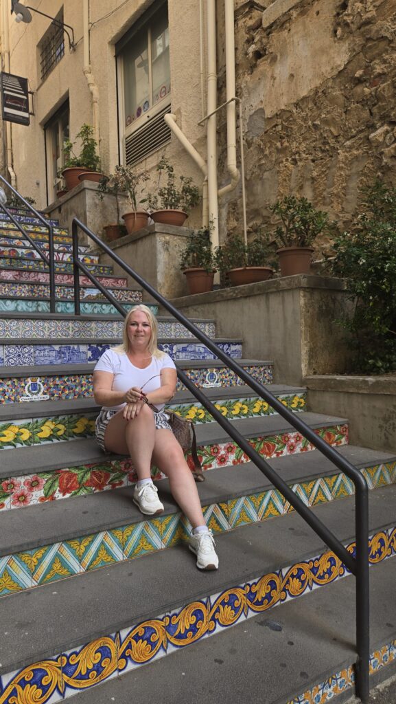 Pictures of me sitting on some steps decorated with tiles in Cefalu, Sicily.